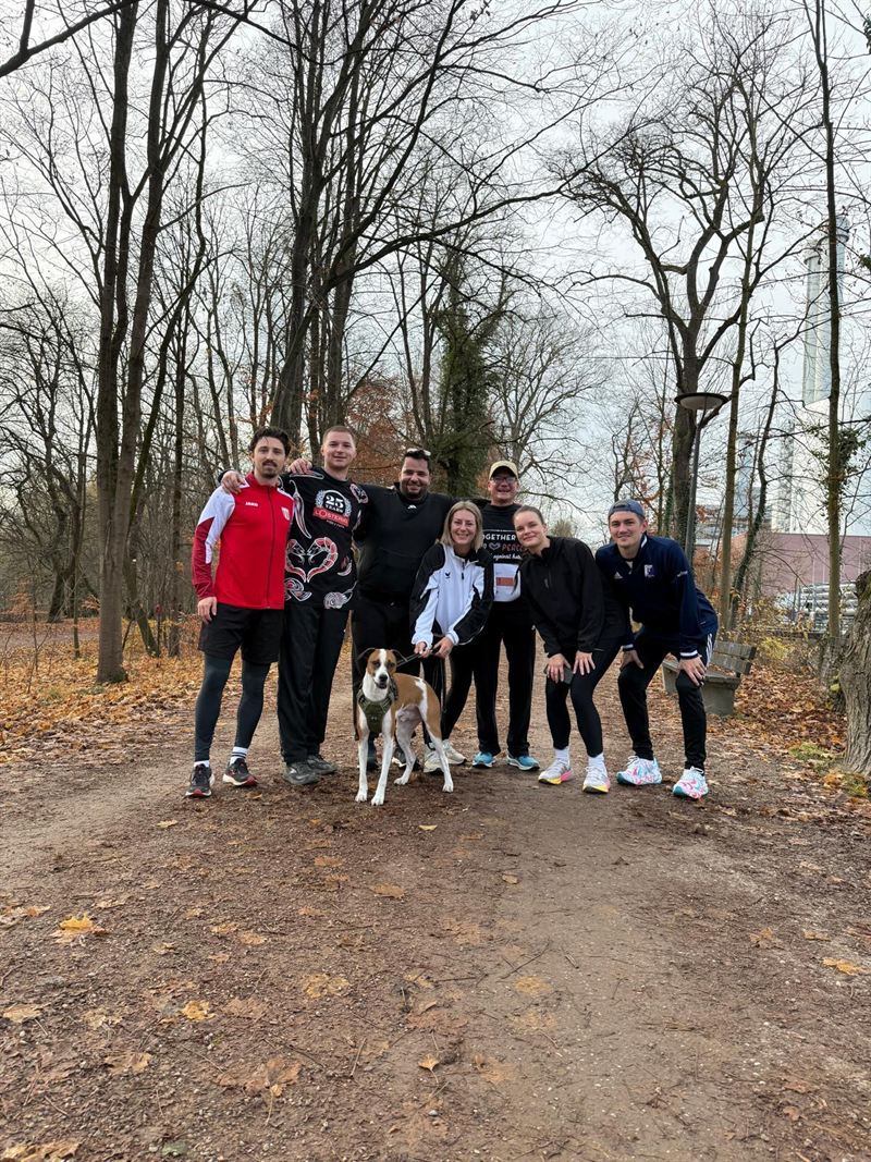 Eine kleine Gruppe der L'Osteria mit Hunden auf einem Waldweg.